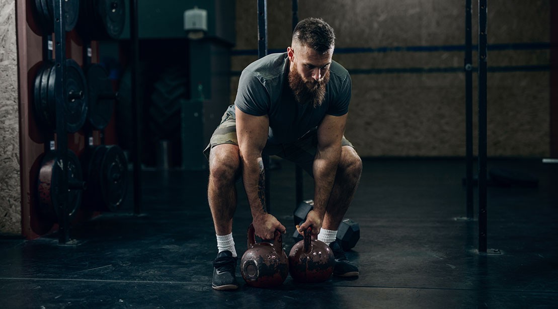 1109 Man Holding Kettlebells shutterstock 1282392403