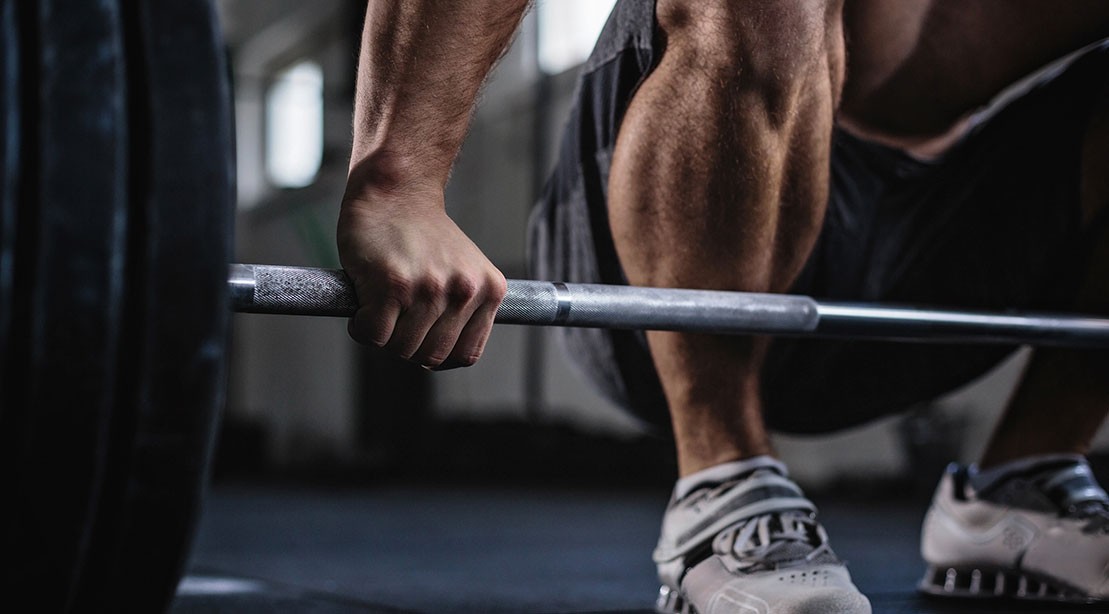 A photo of a person grabbing a barbell. A photo of a person grabbing a barbell.