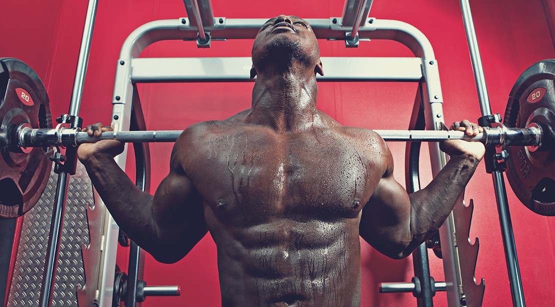Man Squatting While Using a Smith Machine Man Squatting While Using a Smith Machine